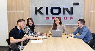 4 Personen sitzen gemeinsam an einem großen Konferenztisch in einem KION Büro